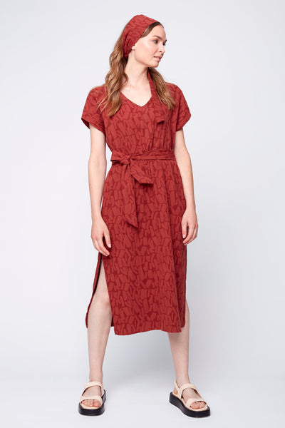 Robe kimono Olivia de JULEI. Droite avec elastic large à la taille, ceinture dans le mêne tissus ajoutée. encolure "v" et fentes sur le coté. Ici portée avec le bandeau Florence dans le même tissus et des sandales Maguire.