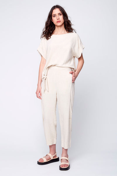 Le pantalon Alice se porte en tenue complète avec son haut Céleste à noeud pour un total look décontracté et chic à la fois. couleur avoine et porté avec des sandales Maguire.